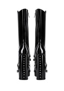 A pair of black patent leather knee-high boots with high block heels, buckle straps, and silver studs, shown from the back on a white background.