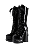 A pair of black patent leather lace-up platform boots with high block heels, decorative side buckles, and glossy vertical silver accents, shown on a plain white background.