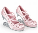 A pair of pink satin Mary Jane-style heels with lace-up straps, bow details on the toes, and metallic silver spikes forming a cage-like structure behind the heels, shown on a white background.