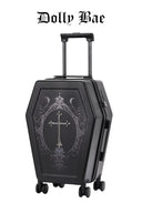 A black coffin-shaped rolling suitcase with a silver gothic cross and ornate filigree design on the front, featuring an extended telescoping handle and four spinner wheels. The brand name 'Dolly Bae' is printed in a gothic font at the top of the image.