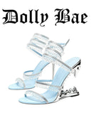 A pair of Dolly Bae light blue high-heeled sandals with silver rhinestone-embellished straps and metallic silver heels, shown on a white background with the Dolly Bae brand name in black gothic font at the top.
