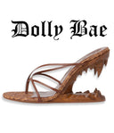A brown leather mule sandal with a unique shark-tooth-inspired heel and textured woven base, shown on a white background with the text 'Dolly Bae' above it.