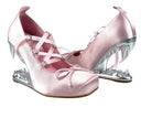 A pair of light pink satin high-heeled shoes with lace-up front straps and metallic silver spiked heels, shown against a plain white background with the text 'Dolly Bae' above them.