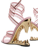 Pink strappy high-heeled sandals with dangling rhinestone fringe and metallic gold shark-tooth spiky wedge heels, shown on a white background.
