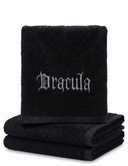 Three folded black towels stacked on a white background, with the top towel embroidered with the word 'Dracula' in a gothic silver font.