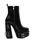 A black leather platform ankle boot with a high block heel, studded platform sole, and silver-tone chain and buckle hardware details, shown against a plain white background.