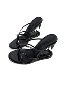 A pair of black patent leather thong sandals with kitten heels, displayed against a plain white background with the brand name 'Dolly Bae' printed in a gothic font at the top.
