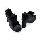 A pair of black platform ankle boots with ruffled lace-up details and block heels, shown on a plain white background with the brand name 'Dolly Bae' printed above.