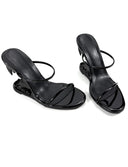 A pair of black patent leather strappy mule sandals with low block heels, displayed on a clean white background with the brand name 'Dolly Bae' printed in a black gothic font above them.