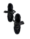 A pair of black lace-up shoes with matching black ribbon bows, shown from a top-down view on a white background with the text 'Dolly Bae' above them.