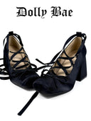 A pair of black velvet high-heeled shoes with criss-cross lace-up front straps and ankle ties, displayed on a white background with the brand name 'Dolly Bae' printed above.