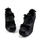 A pair of black gothic-style lace-up shoes with ruffled trim and bow details, displayed on a clean white background with the brand name 'Dolly Bae' printed above.