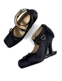 A pair of black satin Mary Jane high heels with ankle straps and bow details, displayed on a clean white background with the brand name 'Dolly Bae' printed in a gothic font above them.