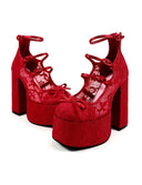 A pair of red platform high-heeled shoes with lace-up ankle straps and bow details, shown on a white background with the brand name 'Dolly Bae' printed above in a black gothic font.