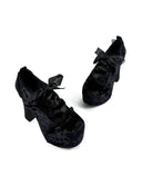 A pair of black velvet high-heeled shoes with bow details, displayed on a clean white background with the text 'Dolly Bae' printed above in a gothic font.