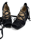 A pair of black lace-up wedge shoes with long ribbon ties, displayed on a white background with the text 'Dolly Bae' above them.