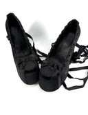 A pair of black platform high heels with long dangling ribbon straps, shown on a plain white background with the text 'Dolly Bae' above them.