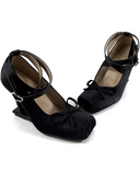 A pair of black Mary Jane-style wedge shoes with ankle straps and bow details, displayed on a plain white background with the brand name 'Dolly Bae' printed above in a black gothic font.