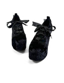 A pair of black velvet lace-up platform shoes with bow details, displayed on a clean white background with the brand name 'Dolly Bae' printed in a gothic font above them.