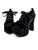 A pair of black velvet lace-up high heels with platform soles and chunky block heels, shown on a plain white background with the text 'Dolly Bae' above them.