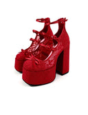 A pair of red lace-up platform high heels with block heels and bow details, shown on a white background with the text 'Dolly Bae' above them.