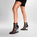 Black high-heeled shoes with unique design on a gray background