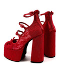 A pair of red platform high heels with ankle straps and block heels, shown on a white background with the text 'Dolly Bae' above them.