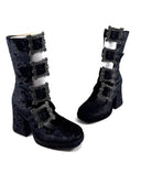 A pair of black velvet ankle boots with silver buckle straps, displayed on a white background with the brand name 'Dolly Bae' printed in a gothic font above them.