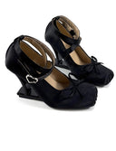 A pair of black kitten heel shoes with ankle straps and bow details, displayed on a white background with the brand name 'Dolly Bae' printed above.
