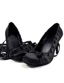 A pair of black lace-up peep-toe heels with long trailing laces, shown on a plain white background with the text 'Dolly Bae' above them.