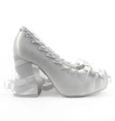 A single silver satin lace-up high-heeled shoe with a block heel and ribbon details, shown on a white background with the text 'Dolly Bae' above it.