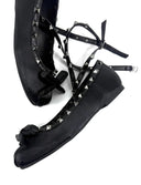 A pair of black pointed-toe flats with studded trim and wraparound lace-up straps, shown on a white background with the text 'Dolly Bae' below.