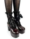 A pair of dark brown and black platform ankle boots with ruffled black lace-up bows, shown on a white background with patterned black socks and the text 'Dolly Bae' below.