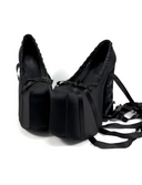 A pair of black platform high heels with long dangling ribbon laces, shown on a plain white background with the text 'Dolly Bae' printed above in a gothic font.