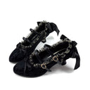 A pair of black gothic-style high-heeled shoes with ruffled trim, lace details, and bow accents, displayed on a white background with the brand name 'Dolly Bae' printed above.