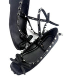 A pair of black leather ballet flats with silver studs, bow details, and wraparound straps, shown on a white background with the text 'Dolly Bae' underneath.