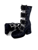 A pair of black gothic-style ankle boots with dark blue crushed velvet panels and multiple silver buckle straps, shown on a white background with the text 'Dolly Bae' above them.