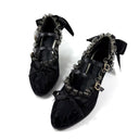 A pair of black gothic-style kitten heel shoes with ruffled lace trim, bow details, and silver chain accents, displayed on a white background with the brand name 'Dolly Bae' printed above.