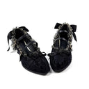 A pair of black lace and velvet Mary Jane shoes with ruffled trim, bows, and silver-tone hardware, displayed on a white background with the text 'Dolly Bae' above them.