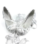 A pair of white satin ballet flats with ribbon bows and lace-up detailing, displayed on a white background with the brand name 'Dolly Bae' printed in a black gothic font above them.