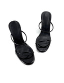 A pair of black patent leather slide sandals with a single thin strap and a mid-height heel, displayed on a white background with the brand name 'Dolly Bae' printed in a black gothic font above them.