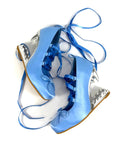 A pair of light blue satin high-heeled shoes with metallic silver wedge heels and blue ribbon laces, displayed on a white background with the text 'Dolly Bae' above them.