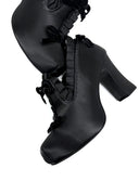 A pair of black high-heeled ankle boots with lace-up front details and ruffled trim, shown on a plain white background with the text 'Dolly Bae' below.