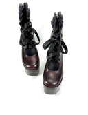 A pair of dark brown platform ankle boots with black ruffled lace-up details, shown against a plain white background with the text 'Dolly Bae' above them.