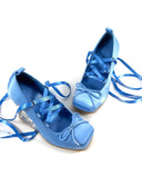 A pair of light blue satin-like lace-up shoes with ribbon ties and clear block heels, shown on a white background with the text 'Dolly Bae' above them.