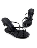 A pair of black patent leather strappy mule sandals with a kitten heel, displayed on a white background with the brand name 'Dolly Bae' printed in a black gothic font at the top.