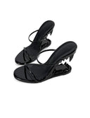 A pair of glossy black strappy mule sandals with sculptural high heels, displayed on a clean white background with the 'Dolly Bae' brand name printed in a gothic font at the top.