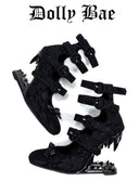 A pair of black gothic-style platform sandals with multiple buckle straps and spiked heels, shown on a plain white background with the text 'Dolly Bae' above them.