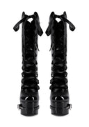 A pair of black patent leather lace-up boots with dramatic bow details at the top and chunky platform soles, shown against a plain white background.