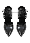 A pair of black pointed-toe stiletto heels with a crocodile-embossed texture, featuring a glossy metallic silver chevron detail on the toe and black lace-up straps with metal spikes, shown against a plain white background.